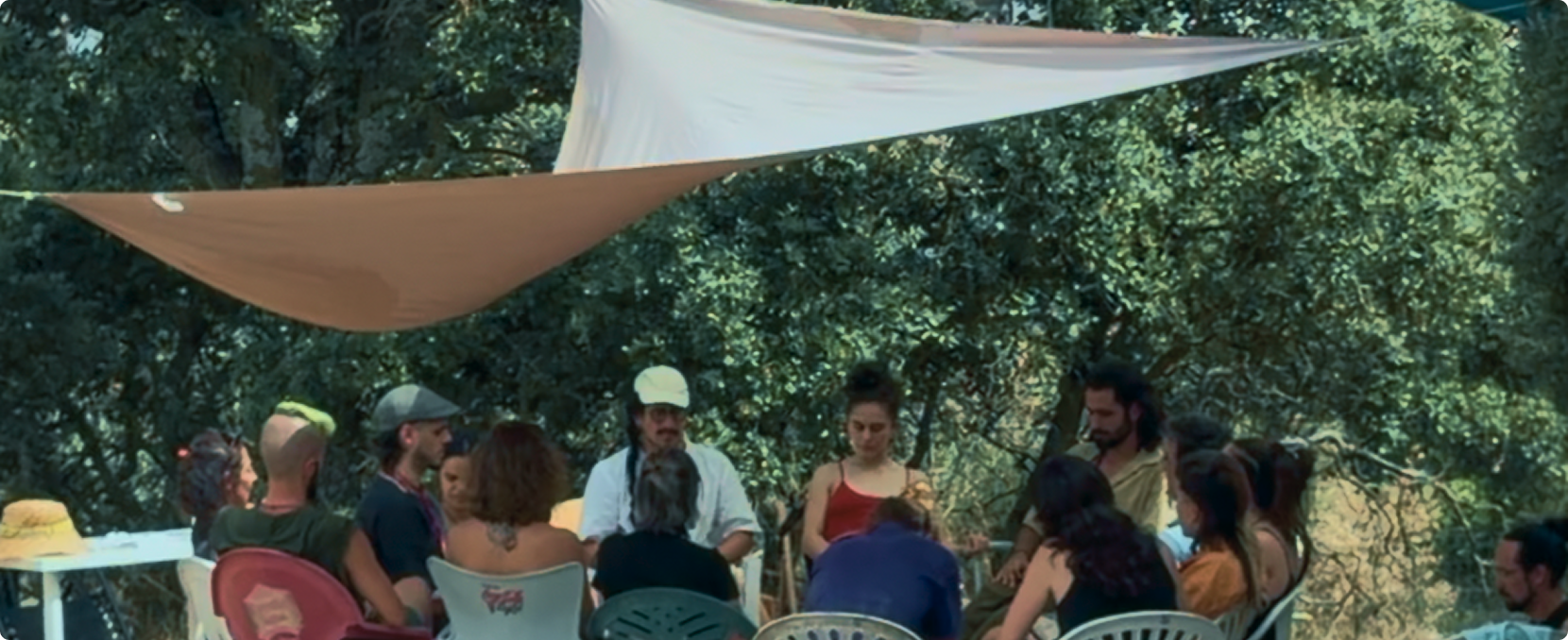 Grupo de personas reunido bajo un toldo en el bosque durante un taller